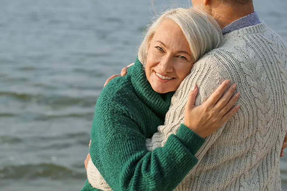 An elderly couple embracing outdoors