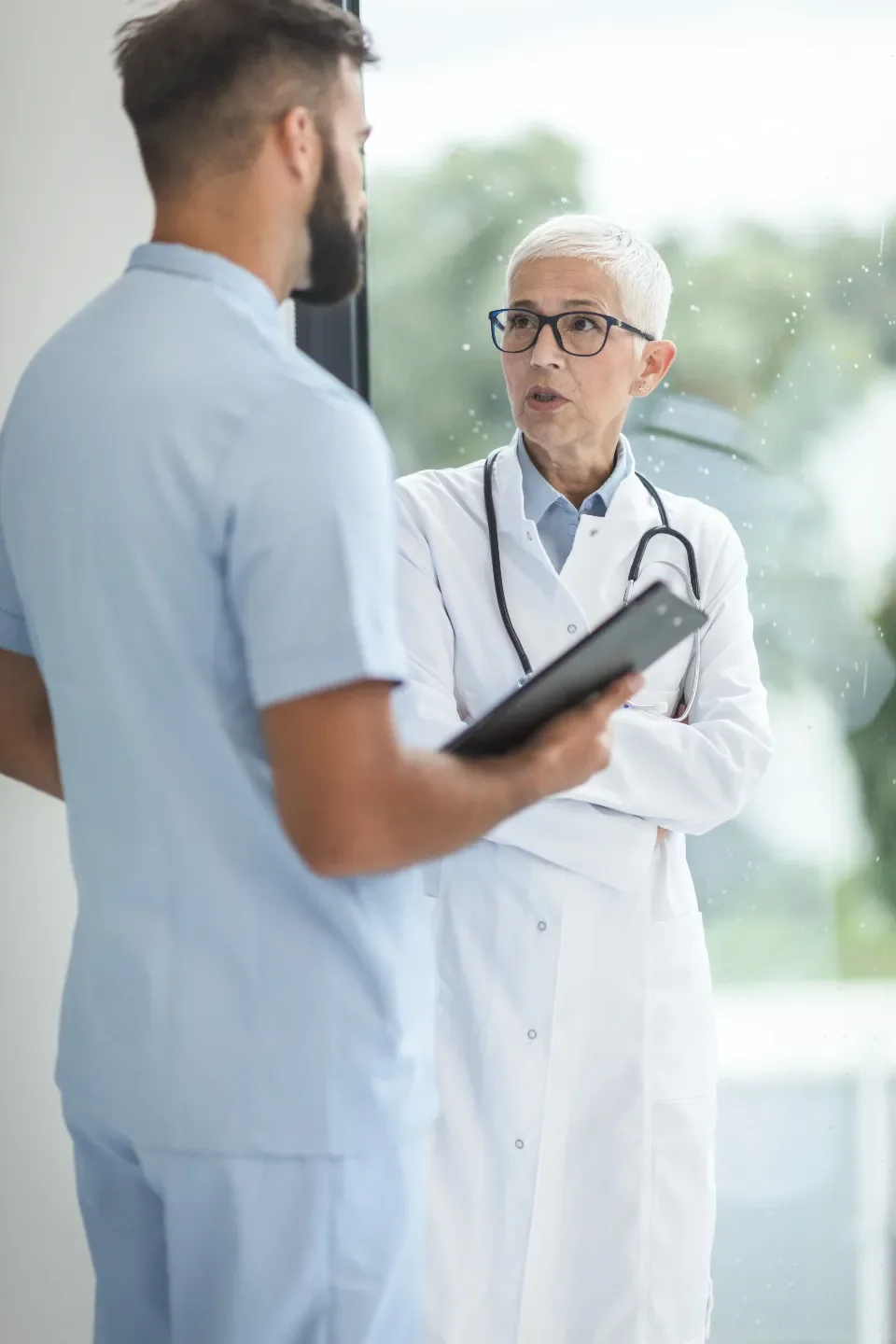Two healthcare workers in a hospital corridor